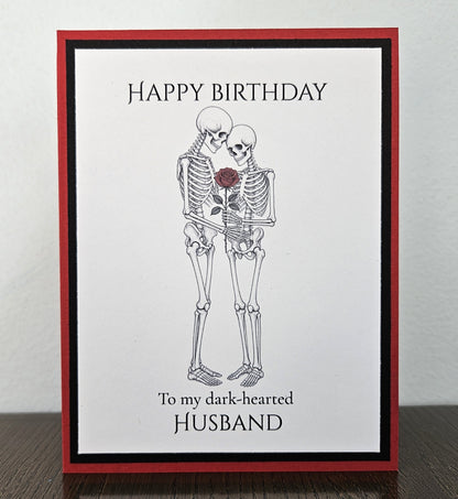Handmade red and black birthday card with an embracing skeleton couple, red rose, and Happy Birthday to my dark-hearted husband wording.