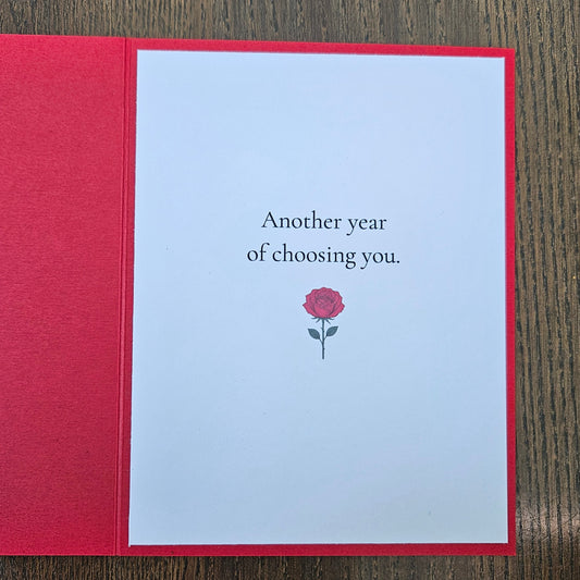Inside of red wife birthday card reading Another year of choosing you, with a small red rose illustration.