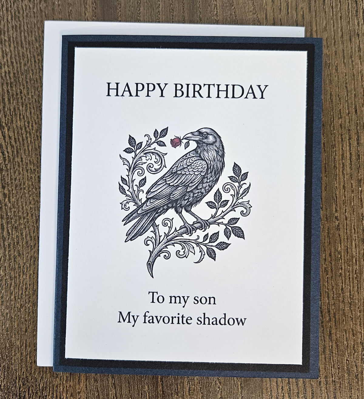 Dark blue and black raven birthday card for a son shown with its white envelope