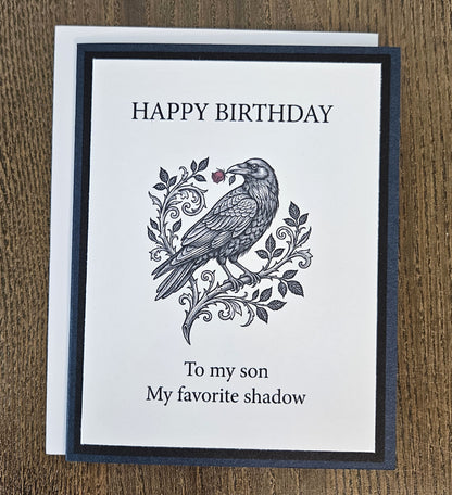 Dark blue and black raven birthday card for a son shown with its white envelope