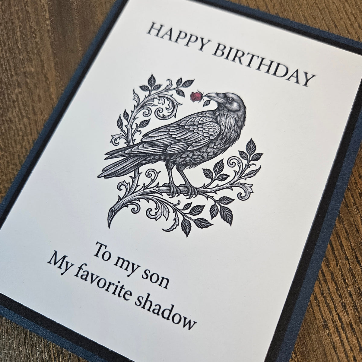 Angled detail of raven feathers, ornamental leaves and dark layered cardstock on son birthday card