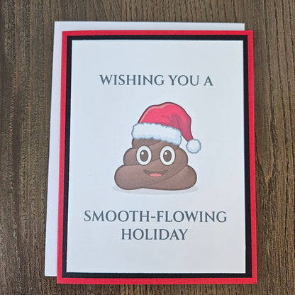 Red and black smooth-flowing holiday poop emoji Christmas card shown with its included white envelope.