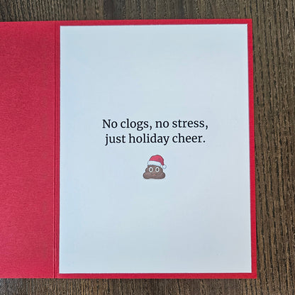Inside of red Christmas card reading No clogs, no stress, just holiday cheer, with a small poop emoji in a Santa hat.