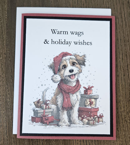 Warm wags and holiday wishes dog Christmas card laid on a wooden surface with its included white envelope.