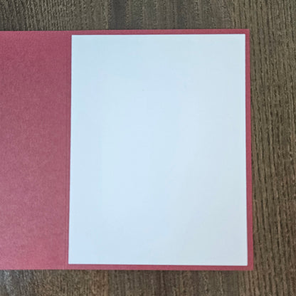 Open muted red Christmas card showing the blank white inside panel for a personal holiday message.