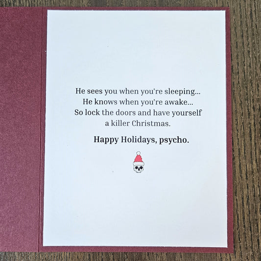 Inside of burgundy Grim Reaper Christmas card with a sleeping and awake rhyme, a killer Christmas punchline, Happy Holidays psycho, and a Santa-hat skull.