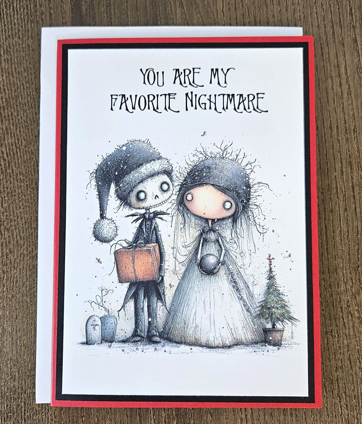 Gothic Favorite Nightmare Christmas card lying flat with its white envelope, showing the spooky couple illustration and red and black cardstock layers.