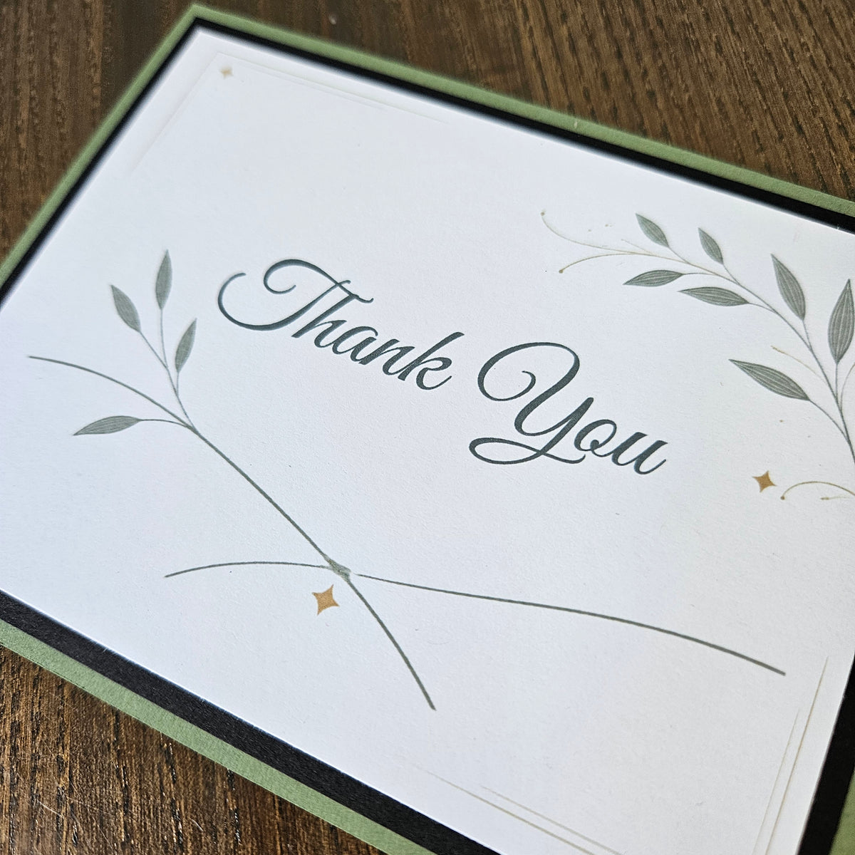 Botanical Thank You card with sweeping stems, green leaves and small gold-colored printed star accents.