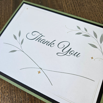 Botanical Thank You card with sweeping stems, green leaves and small gold-colored printed star accents.
