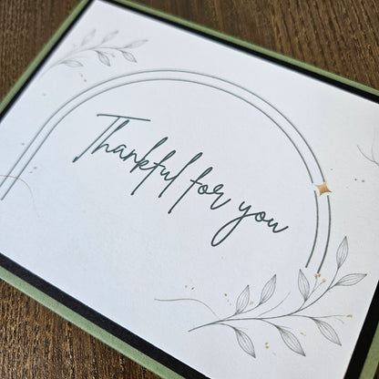 Thankful for you card with curved line framing and fine botanical foliage on a white front panel.