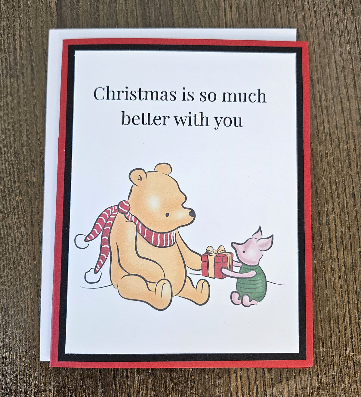 Winnie the Pooh and Piglet Christmas friendship card with a white envelope on a wooden surface.