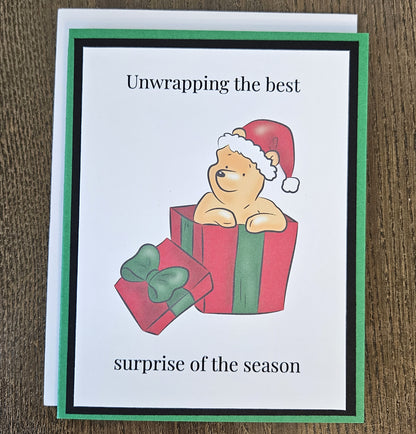 Green and black Winnie the Pooh Christmas gift box card with a white envelope on a wooden surface.