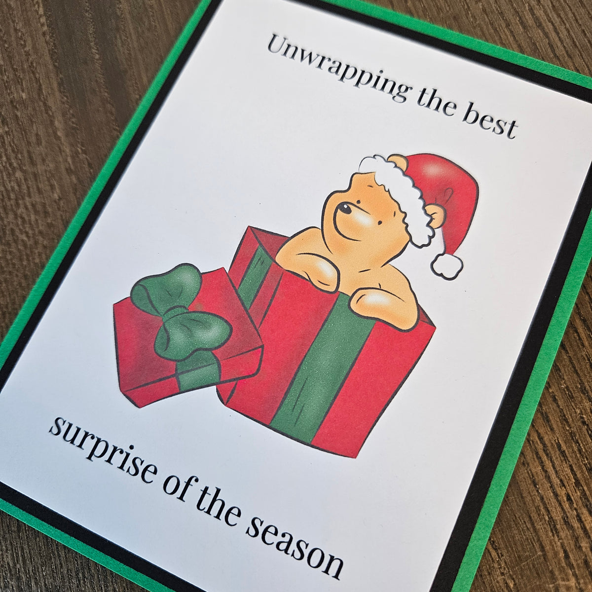 Angled close-up of Winnie the Pooh in a Santa hat and gift box beneath the words Unwrapping the best surprise of the season.
