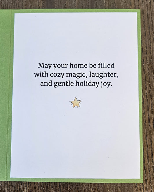 Printed inside of a green Christmas card reading May your home be filled with cozy magic, laughter, and gentle holiday joy, with a yellow star below.