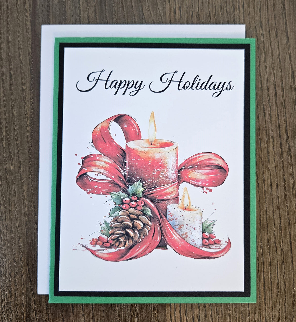 Angled close-up of the printed candle, red ribbon, holly and pinecone design beneath Happy Holidays lettering.