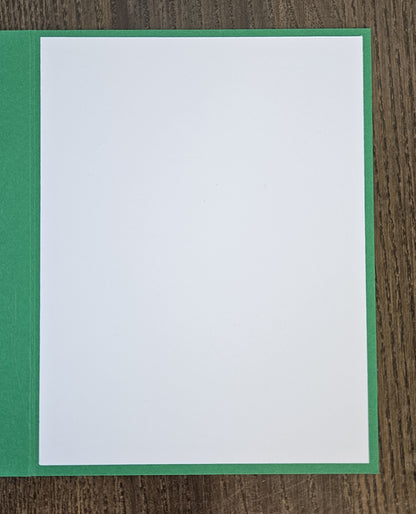 Open green holiday card showing a blank white interior writing panel.
